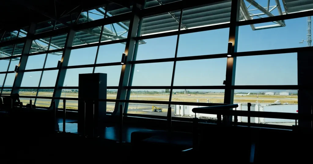 Saguão de aeroporto na contraluz, com janelas amplas voltadas para a pista